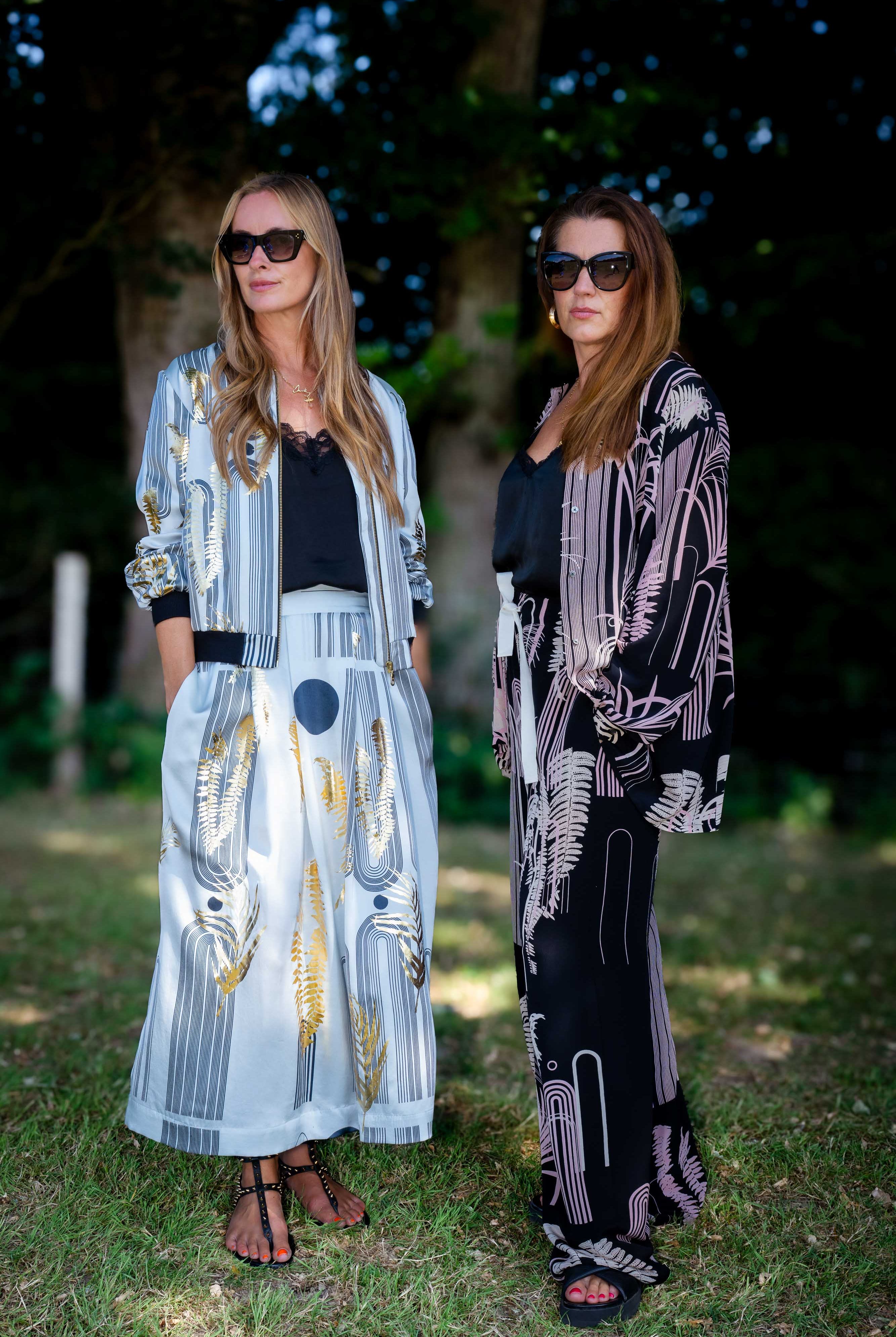 Two women standing outdoors wearing stylish outfits with abstract patterns.
