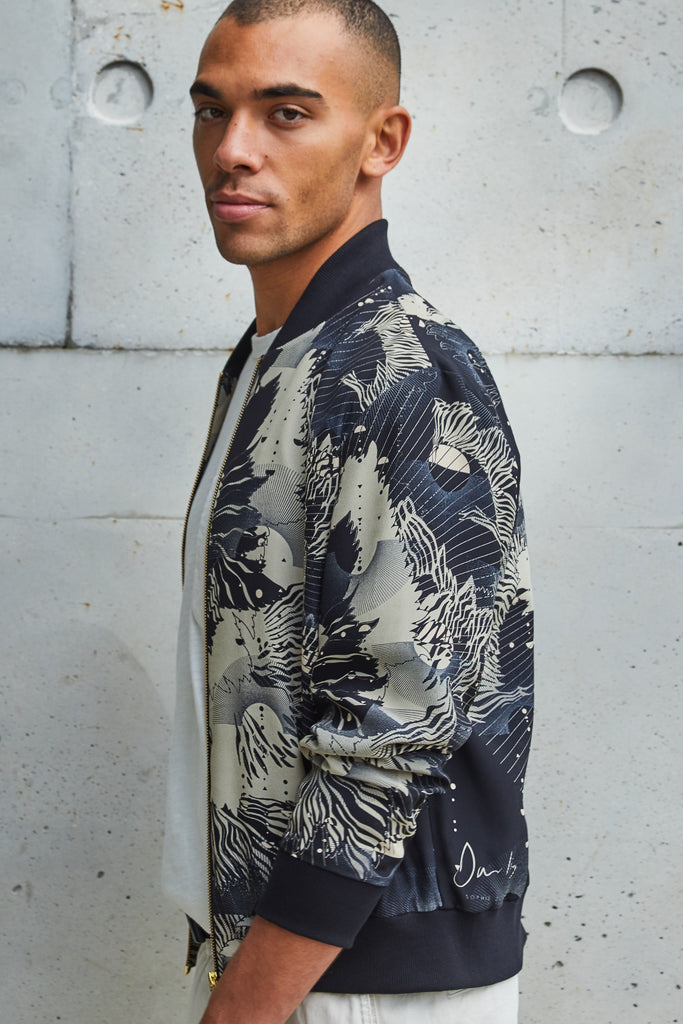 A man wearing a silk mens bomber jacket in a deep navy and cream print abstract floral print