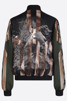 The back of a hand printed silk bomber bomber jacket with hand printed designs in black, olive green and rose gold