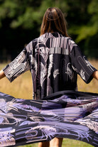 Person holding a large piece of fabric with a black and white pattern in a field
