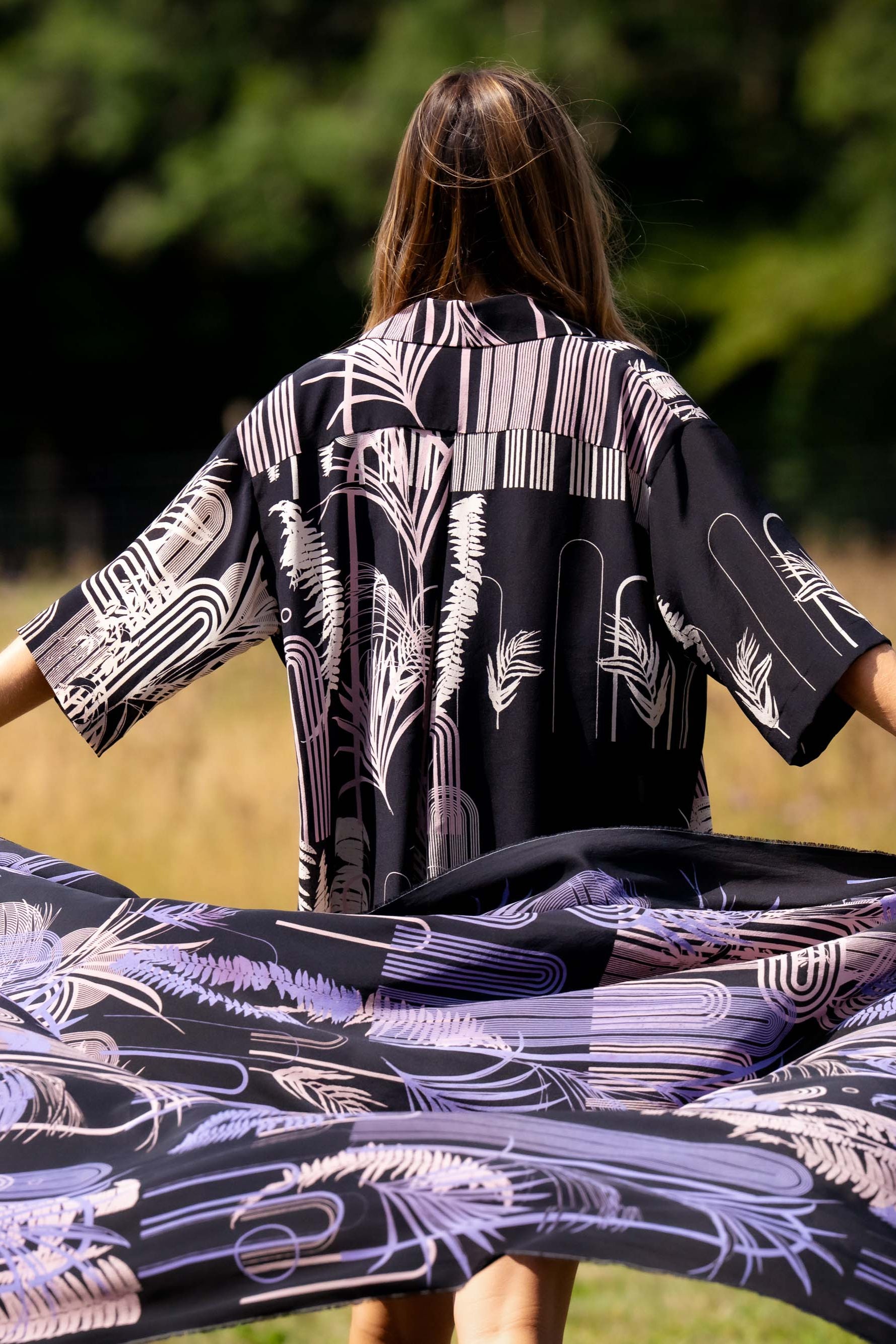 Person holding a large piece of fabric with a black and white pattern in a field