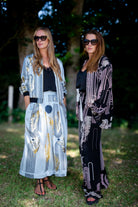 Two women standing outdoors wearing stylish outfits with abstract patterns.