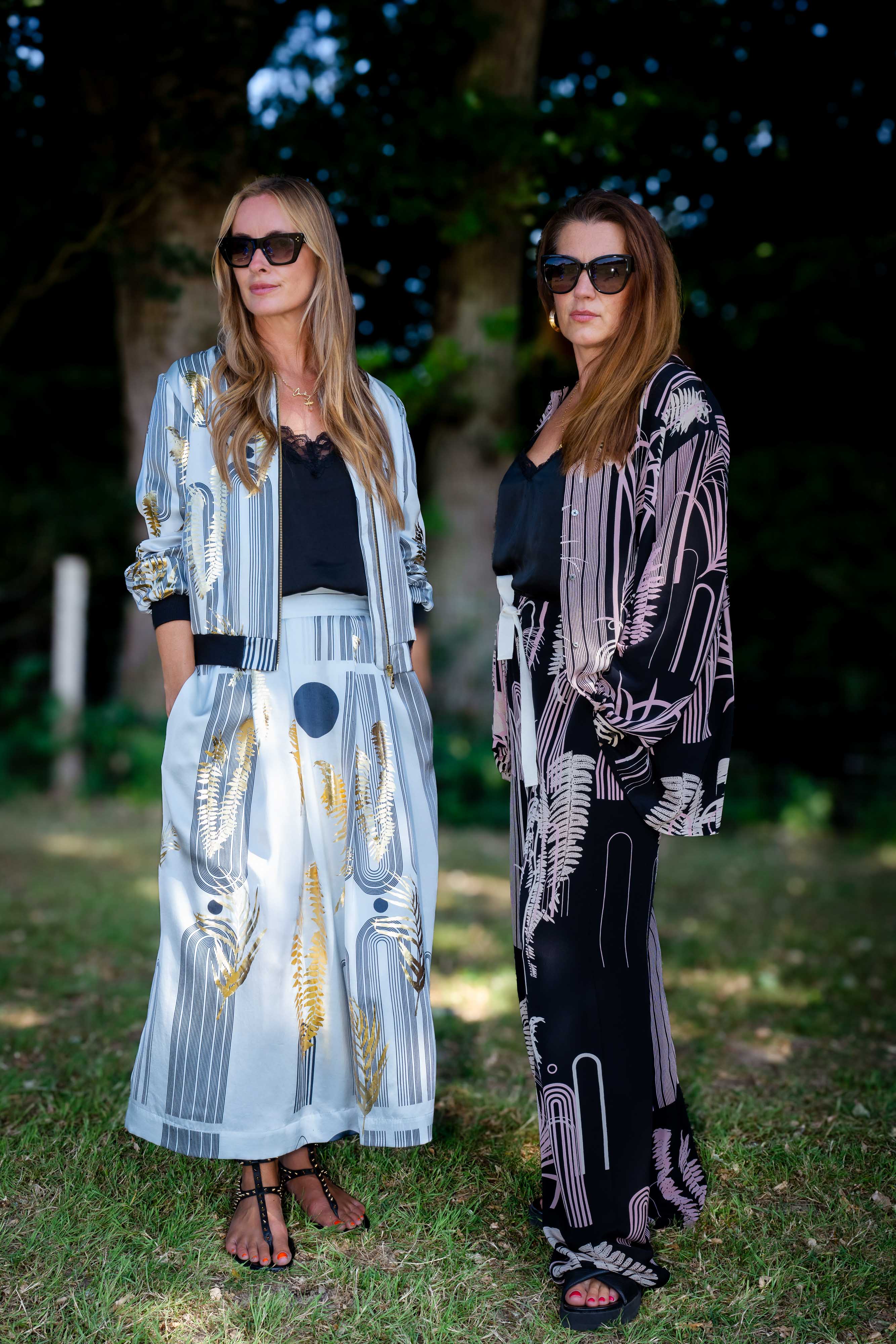 Two women standing outdoors wearing stylish outfits with abstract patterns.