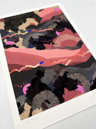 A giclee print in black and pink with a landscape design and bright pink suns