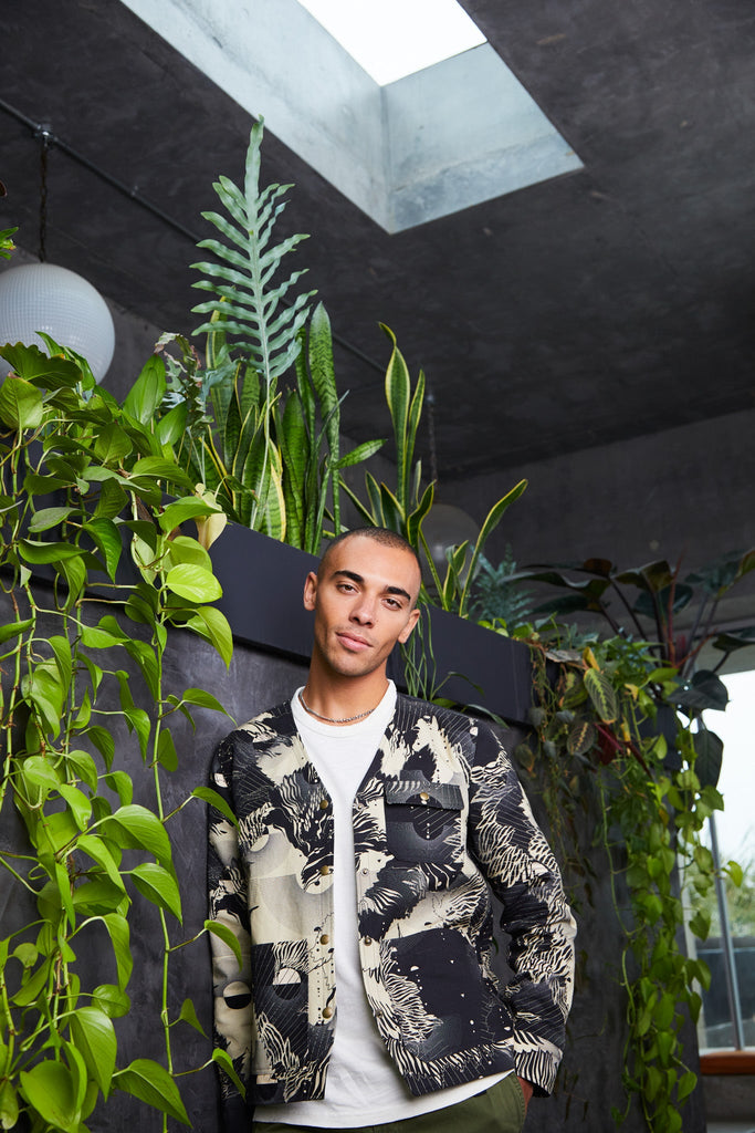 A man wearing a cotton mens utility jacket with a navy and cream abstract floral print