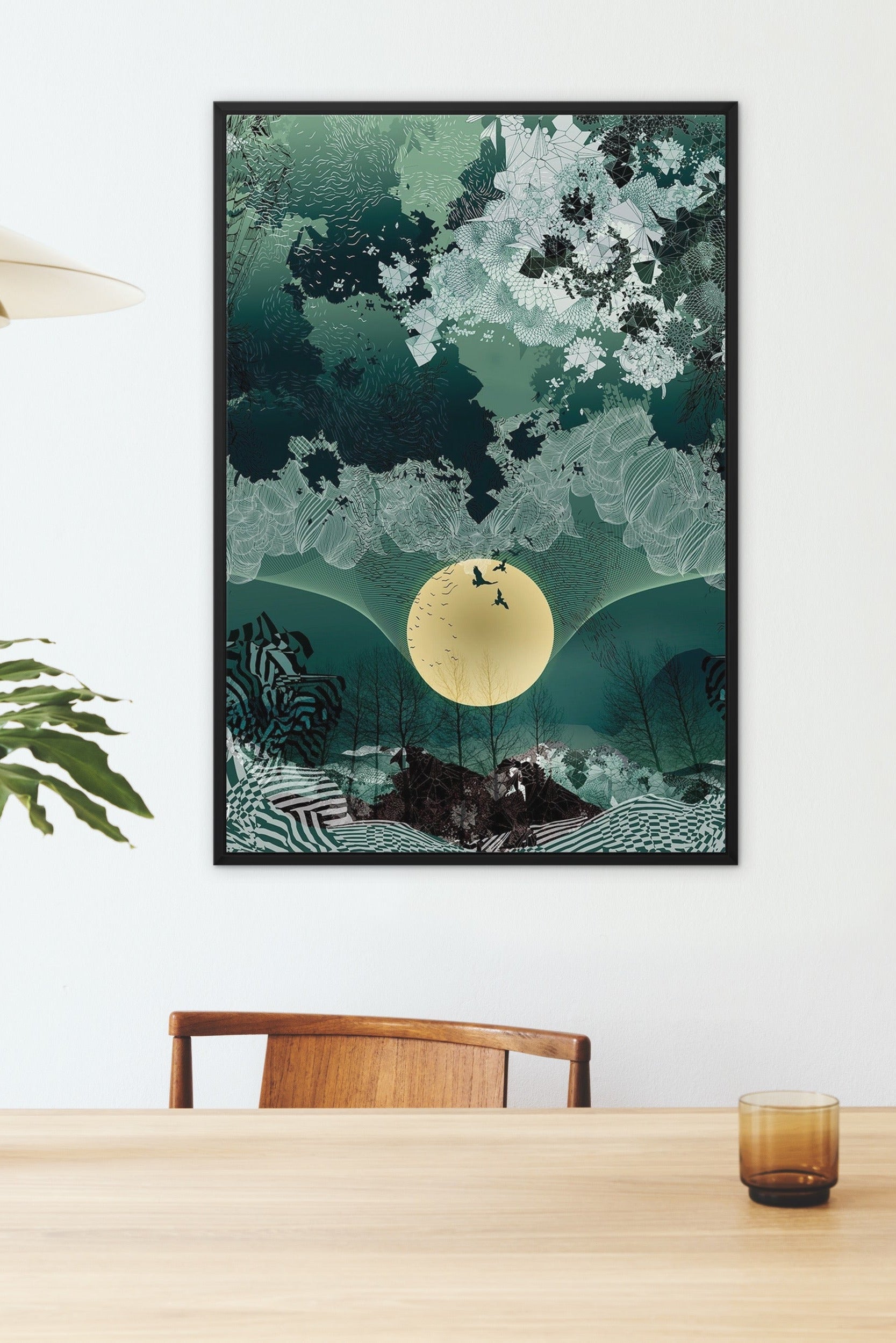 Framed canvas print on a wall above a wooden table with a glass and chair.
