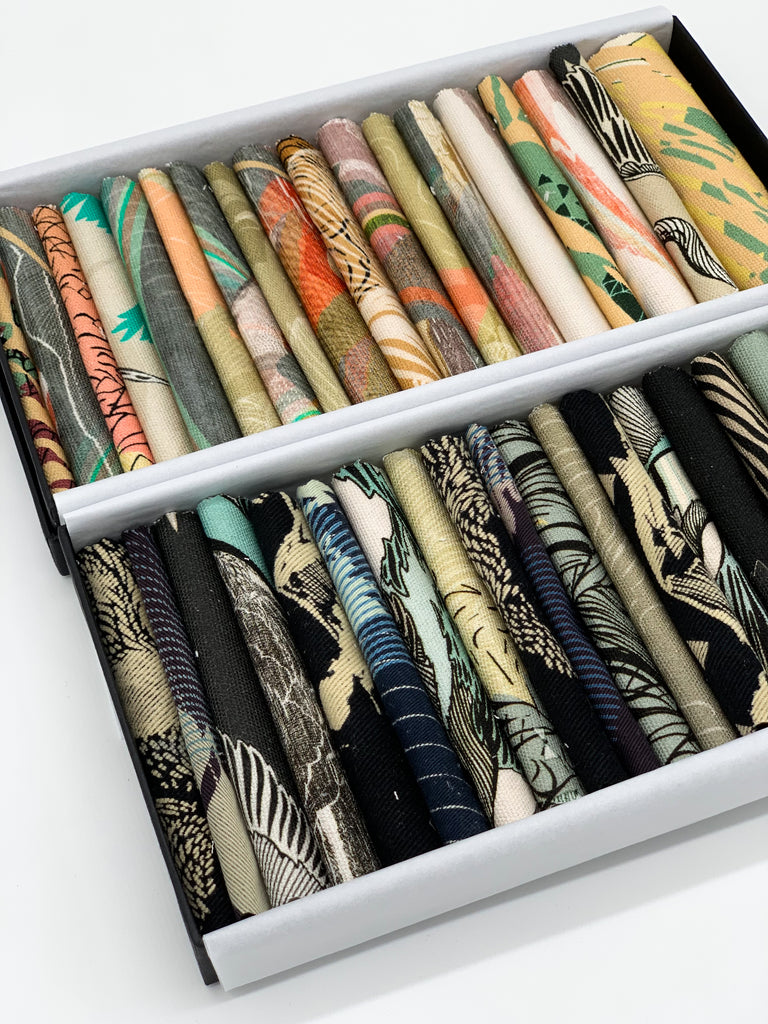 An off- cut fabric box containing dark tone and earth tone pieces 