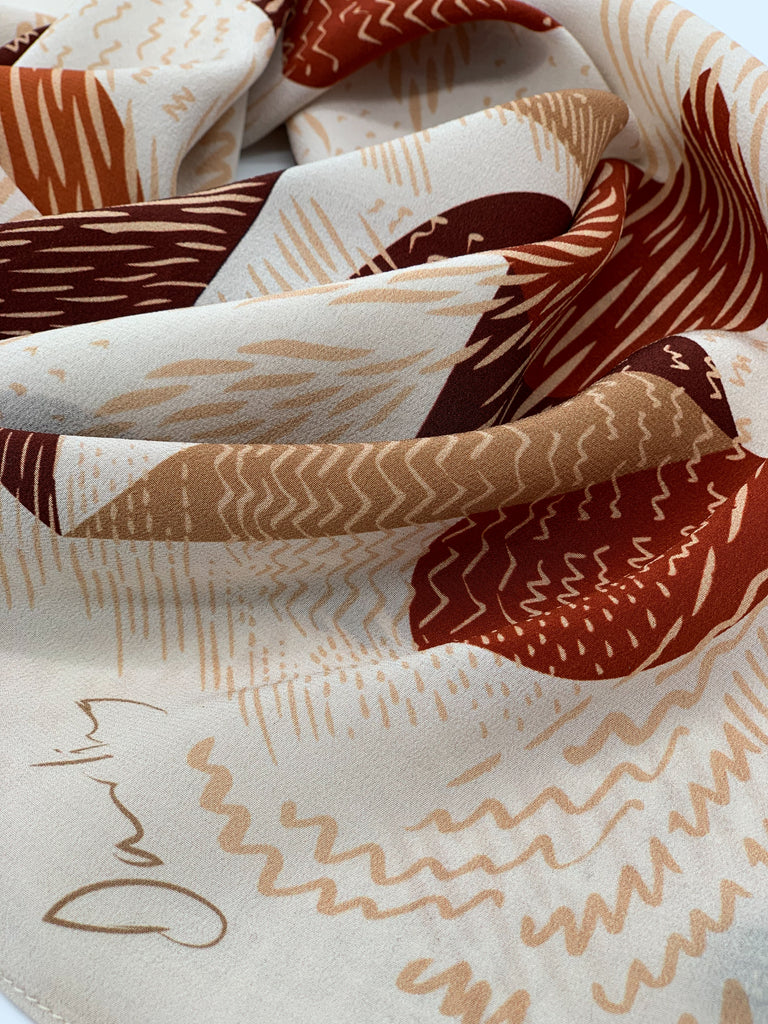 A close up of a silk printed scarf in earthy tones