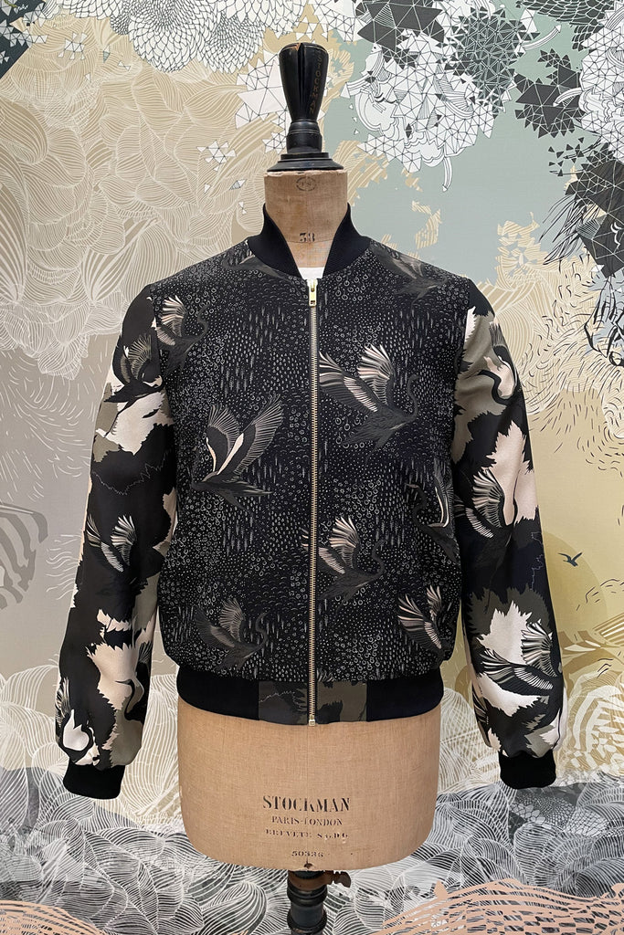 The front of a silk bomber jacket in shades of green with a camo and a stalk design