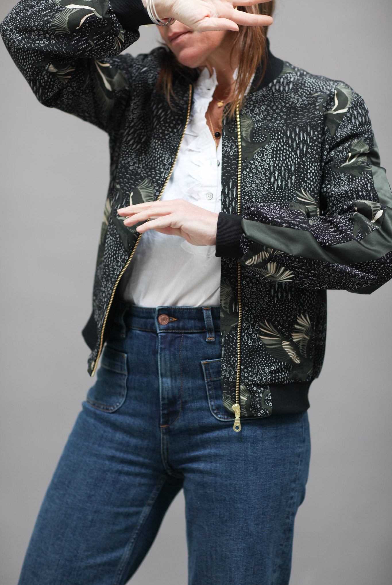A woman wearing a printed silk bomber in green and black