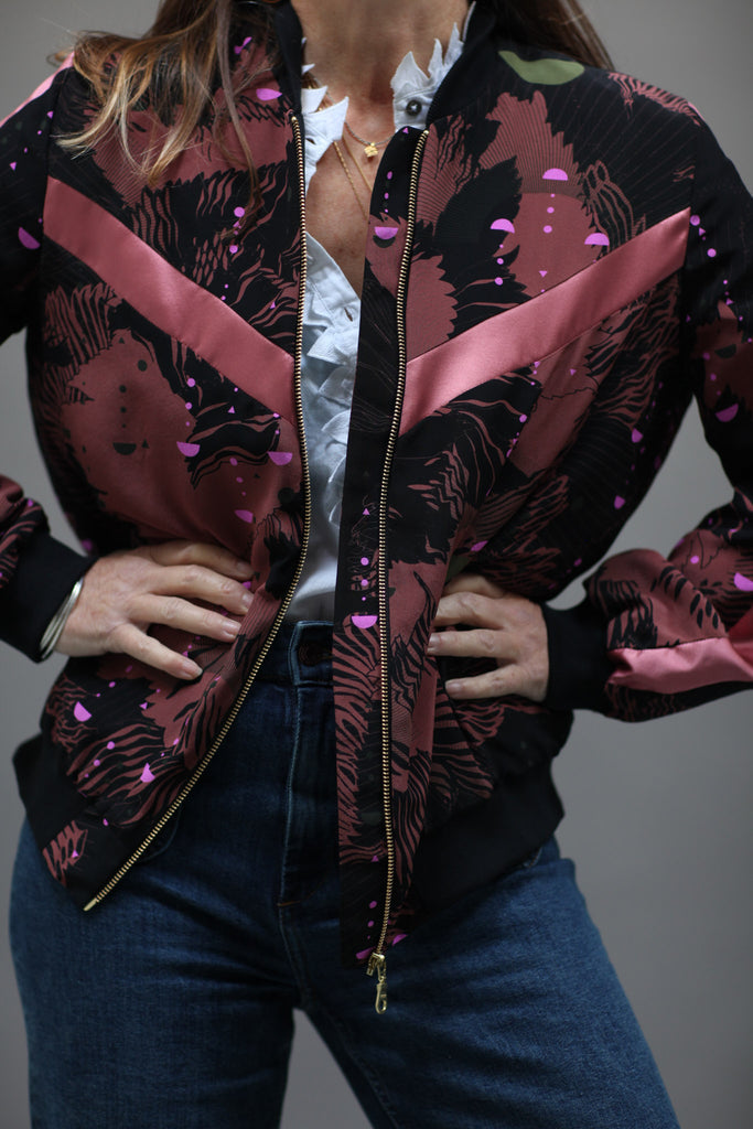 A woman wearing a silk printed bomber jacket in black and pink