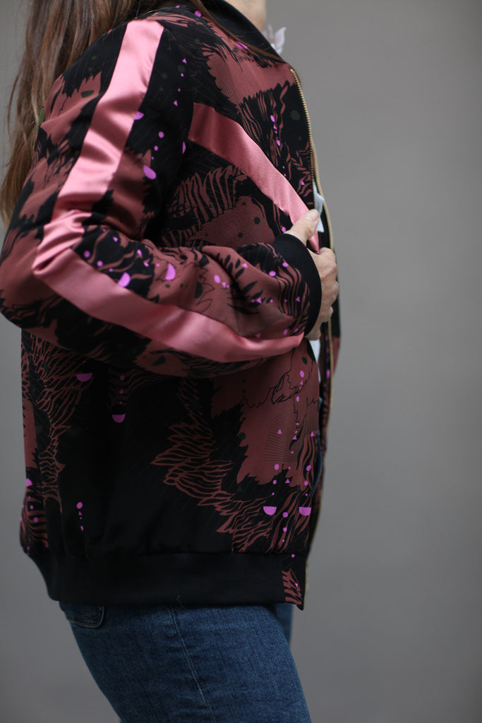 A woman wearing a silk printed bomber jacket in black and pink