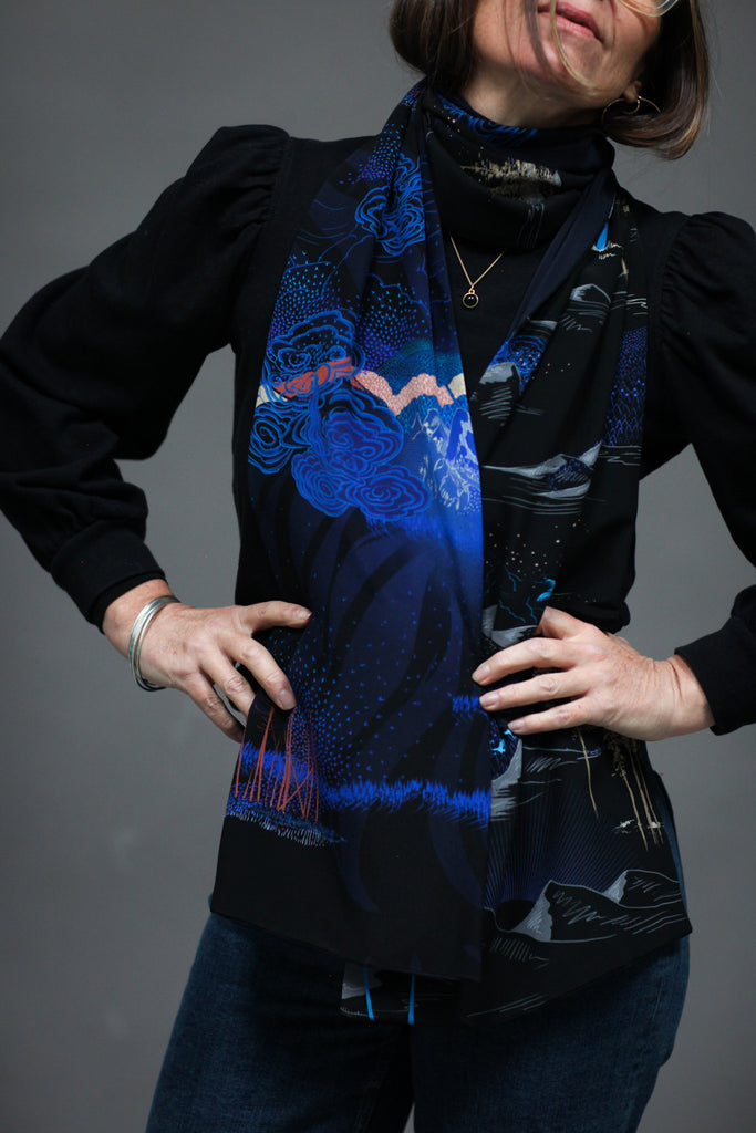 A woman wearing a printed silk scarf in black and blue