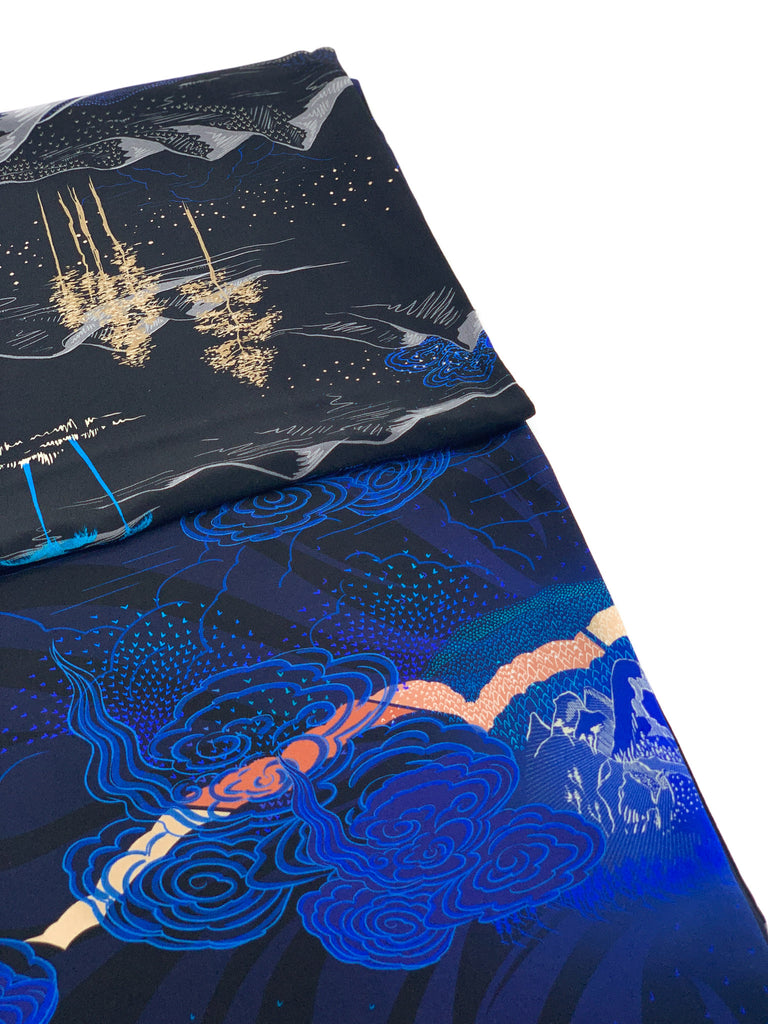 A close up of a printed silk scarf in black and blue