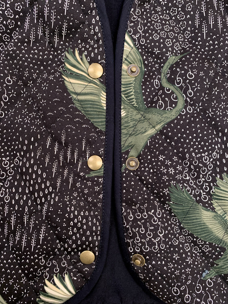 An up close of a cotton drill quilted waistcoat in black, green and white