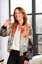 Woman wearing a Sophie Darling Sunrise silk bomber jacket in orange and black with sunrise design