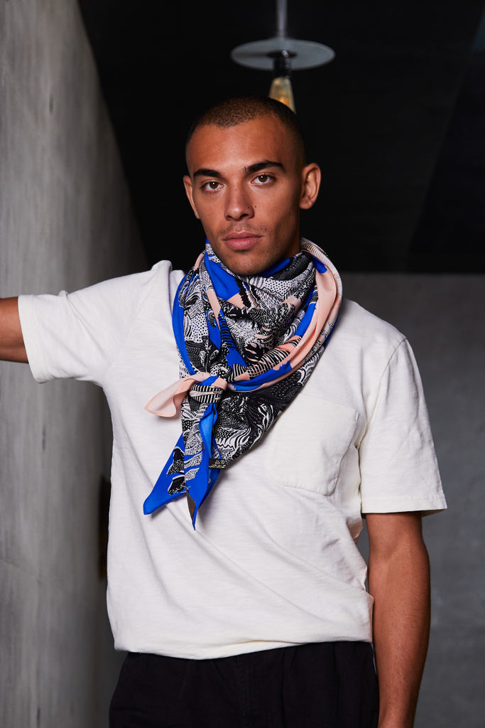 A man wearing a silk scarf, with a pink, blue and monochrome botanical print