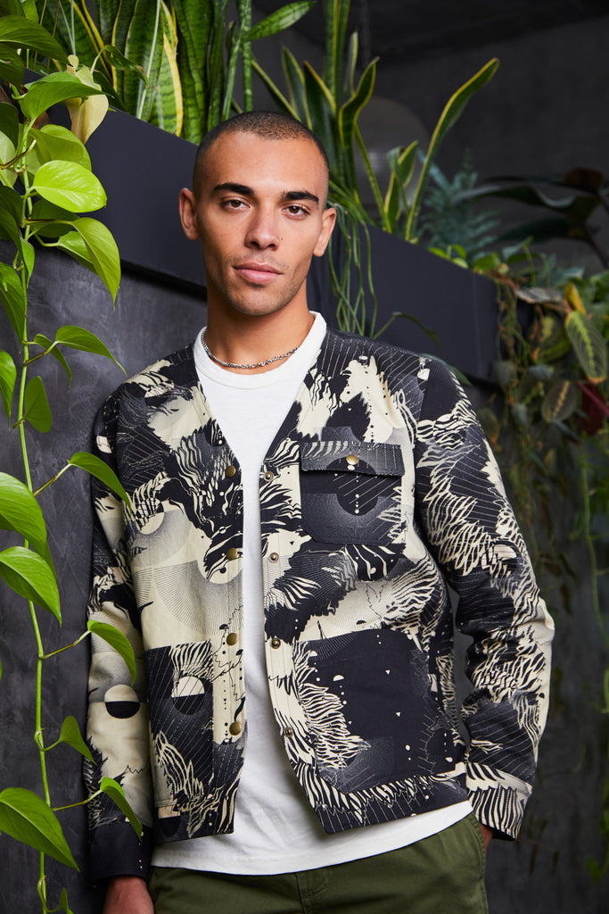 A man wearing a cotton mens utility jacket with a navy and cream abstract floral print