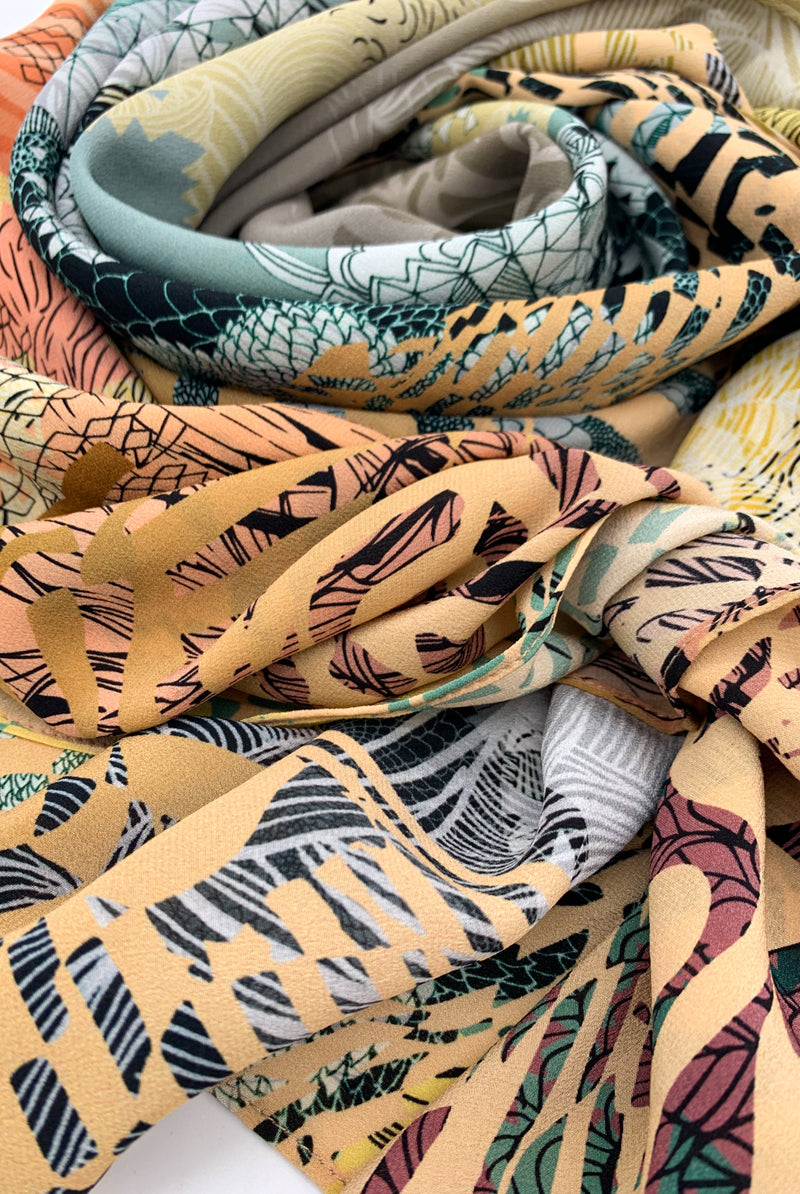 Close up of a silk scarf sunrise design in muted yellows, greens and coral