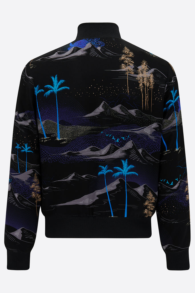 The back of a silk mens bomber jacket with a landscape all over print in black, bright blue and tan