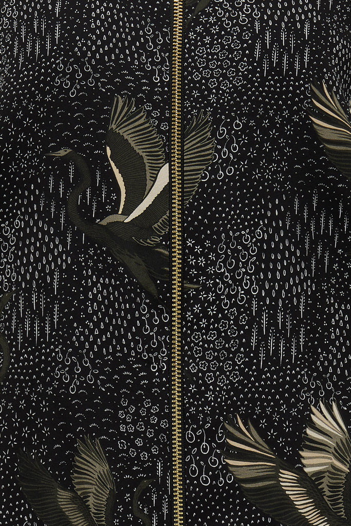 A close up of a printed silk bomber in green and black