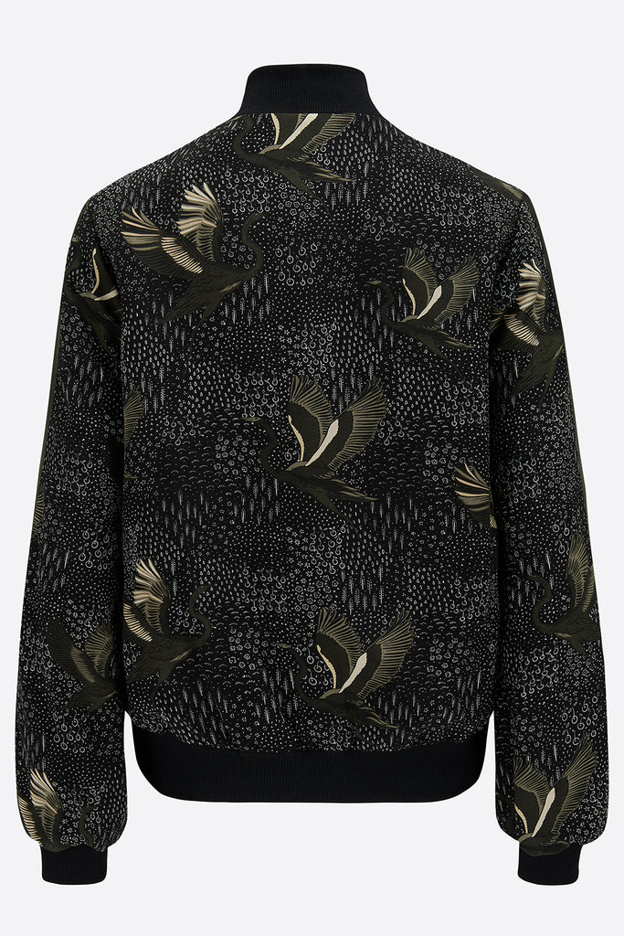 The back of a printed silk bomber in green and black