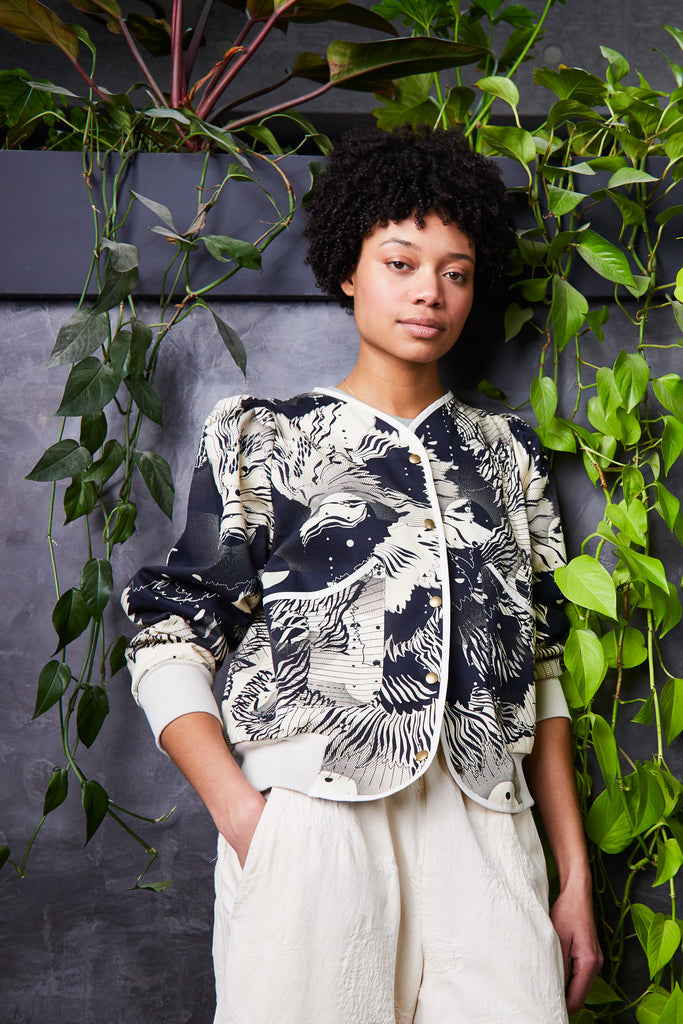 A woman wearing a cotton jacket with an abstract floral print in navy and cream