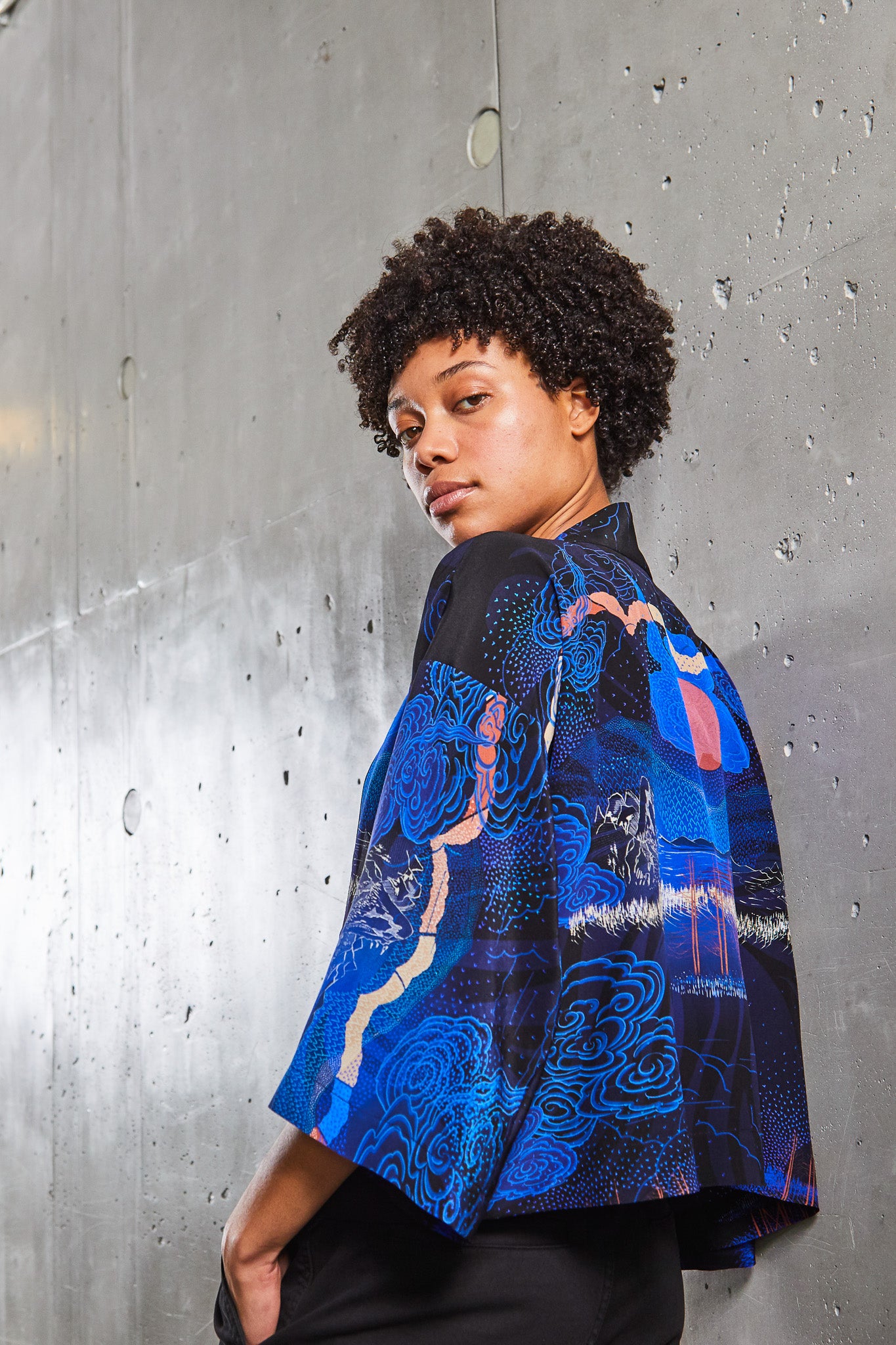 A woman wearing a short Silk Kimono Jacket with Japanese landscapes in blues and pinks