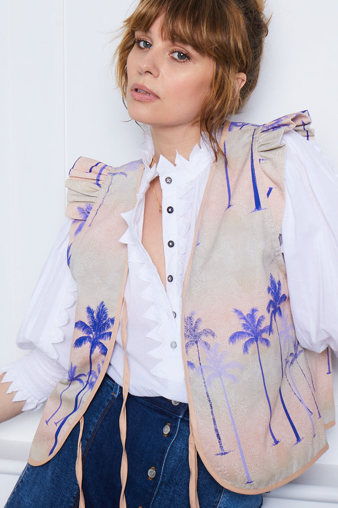 A woman wearing a pink tencel lined waistcoat with a palm tree print