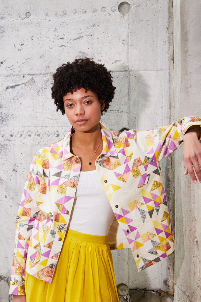 A woman wearing a cotton utility jacket in a geometric triangle design in yellow and pink