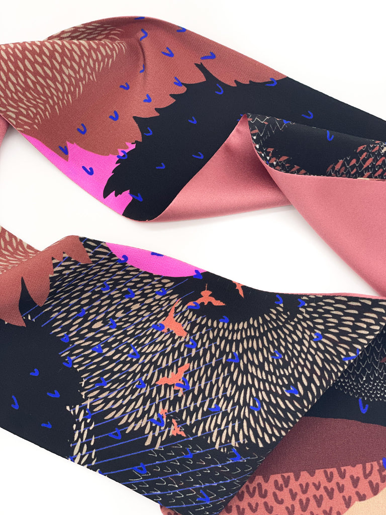 A close up of a silk printed headscarf in black and pink