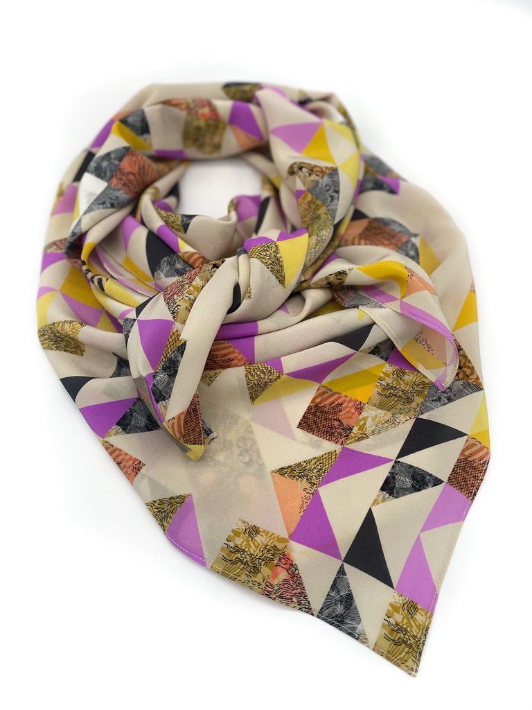 A silk scarf in a geometric pink and yellow print against a white background