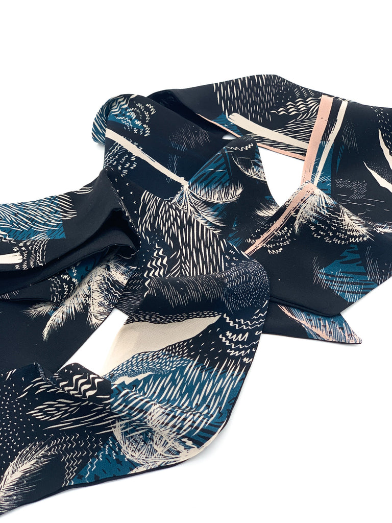 A close up of a silk printed headscarf in blue and black 