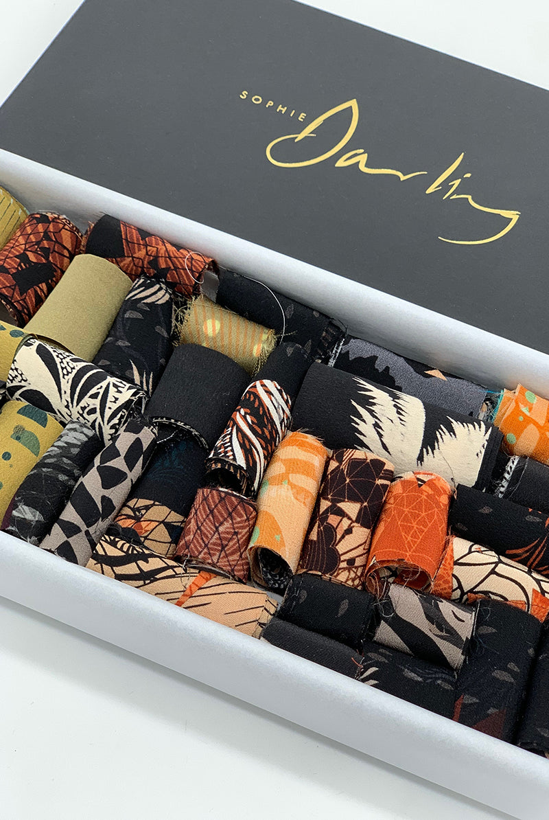 A ribbon box containing earth tone fabric pieces 