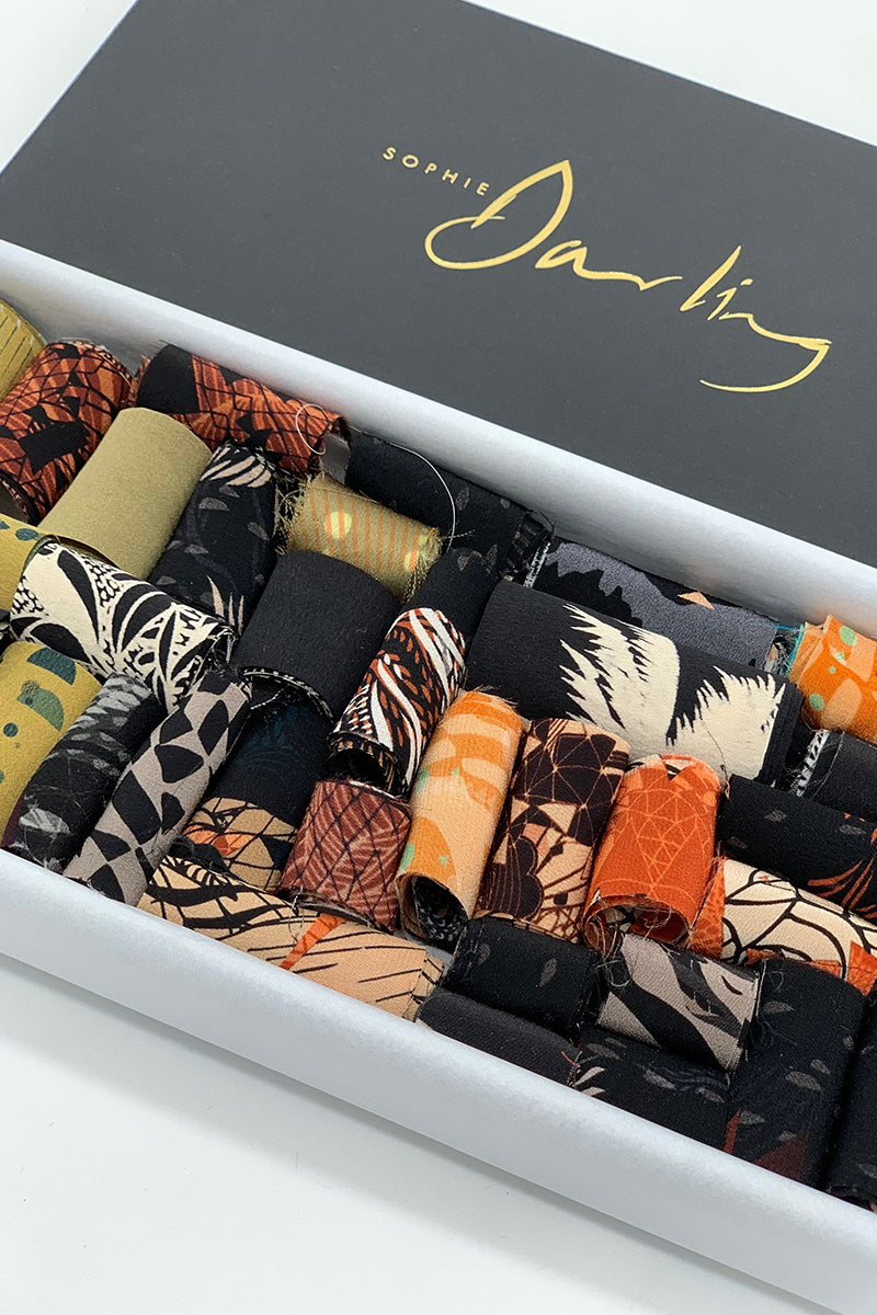A ribbon box containing earth tone fabric pieces 
